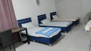 a room with three beds and a table and a desk at RelaxAlkhuwirHostel in Muscat