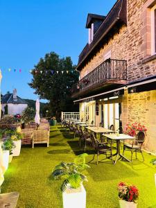 a patio with tables and chairs and a building at Hôtel Le Castanea Entre Aurillac et Marcolès Auvergne in Roannes-Saint-Mary