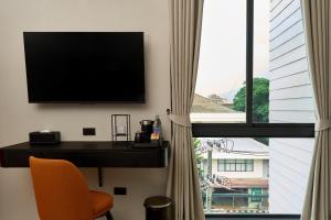 a room with a tv and a chair and a window at Lantern Chiang Mai Night Bazaar Hotel in Chiang Mai