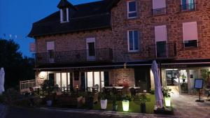 a building with tables and chairs in front of it at Hôtel Le Castanea Entre Aurillac et Marcolès Auvergne in Roannes-Saint-Mary