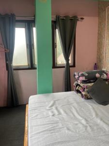 a bed in a room with two windows at The Rainbow Inn in Sonāda +2 photos