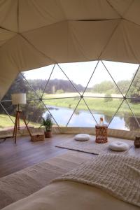 a bed in a tent with a view of a lake at Glempingosta in Bauska