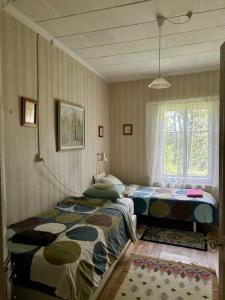 a bedroom with two beds and a window at Tunnelmallinen maalaistaloelämys in Vehmaa