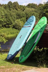 two surfboards sitting on a table next to a river at Glempingosta in Bauska +3 photos
