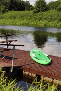 a green kayak sitting on a dock on a lake at Glempingosta in Bauska