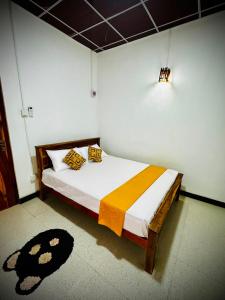 a bedroom with a bed with a yellow and orange blanket at Nethmini Leege Cottage in Kibissa