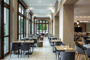 a row of tables and chairs in a restaurant with windows at Crowne Plaza Paris Marne-la-Vallée in Magny-le-Hongre