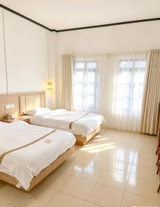 a hotel room with three beds and windows at Tea time B&B 叙茶时光客栈 in Luang Prabang