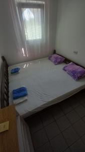 a large white bed with purple pillows and a window at Nikola CG in Sutomore