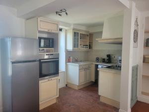 a kitchen with white cabinets and a stainless steel refrigerator at Logis de l'Éperon Laon in Laon +7 photos