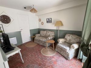 a living room with a couch and a chair and a tv at Logis de l'Éperon Laon in Laon