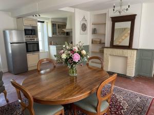a kitchen with a wooden table with a vase of flowers at Logis de l'Éperon Laon in Laon