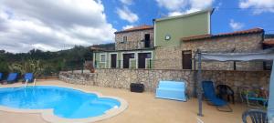 a house with a swimming pool and blue chairs at Casa De Campo De Oliveiras in Penela