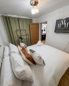 a bedroom with a large white bed with pillows at Modern Large 5-Bed-2 Baths-Parking-Great for Groups-Contractors-Families-Royal Leamington Spa-Warwickshire-By The Home Makers Hub in Leamington Spa
