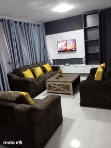 a living room with two couches and a tv at Green Harvest BnB in Newmansford