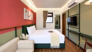 a bedroom with a bed and a couch and a tv at Joi Boutique Bãi Trước in Vung Tau
