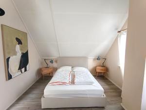 a bedroom with a white bed in a attic at Buitenplaats 67 with optional sauna in Callantsoog +12 photos
