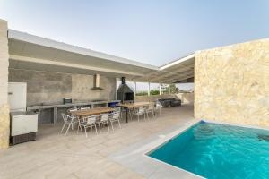 an outdoor kitchen and dining area with a swimming pool at Bender House in Moralet