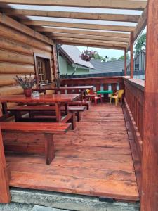 a wooden deck with picnic tables and chairs at Chata Borovec in Veľké Borové