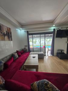 a living room with a red couch and a tv at Appartement RDJ in Dar Hamida