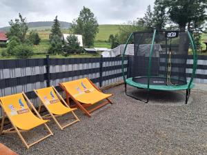 two chairs and a trampoline sitting next to a fence at Chata Borovec in Veľké Borové