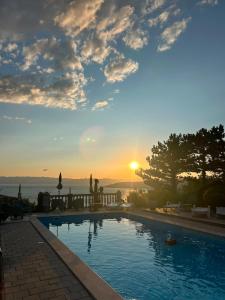 a swimming pool with a sunset in the background at Casa Perla Holidays in Juraši