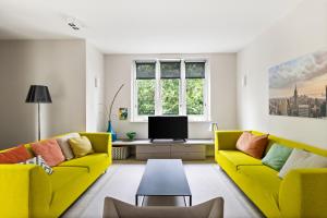 a living room with two yellow couches and a tv at Mezger Lodges in Domburg