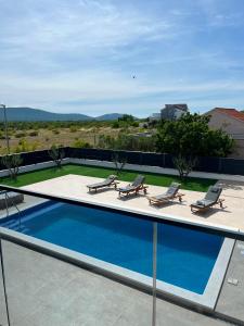 a swimming pool on the roof of a building with lounge chairs at Villa Karla Luxury Pool Villa near Šibenik & Krka in Konjevrate