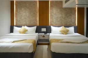 two beds in a room with two windows at Hotel Krushnai Deluxe in Nandre