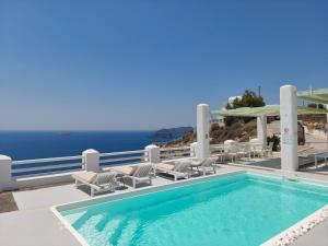 a swimming pool with chairs and the ocean in the background at The Cliff Reflections - Adults Only in Megalochori