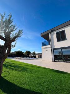 a building with a tree in front of a yard at Villa Karla Luxury Pool Villa near Šibenik & Krka in Konjevrate