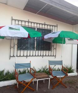 two chairs and two umbrellas next to a building at Yayi Maria in Río Hato