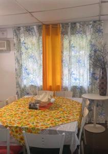 a dining room with a table with a yellow curtain at Yayi Maria in Río Hato
