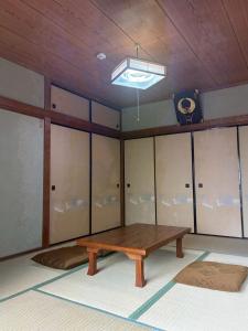 a room with a wooden table and a ceiling at ゲストハウス美和館 in Imabari