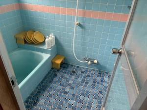 a blue tiled bathroom with a tub and a sink at ゲストハウス美和館 in Imabari