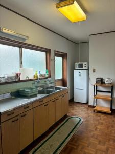 a kitchen with a sink and a refrigerator at ゲストハウス美和館 in Imabari