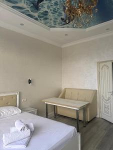 a room with two beds and a table and a ceiling at Rodnik in Almaty +4 photos
