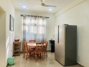 a dining room with a table and chairs and a refrigerator at Dee Holidays in Moratuwa
