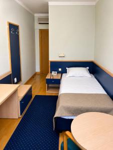 ein Schlafzimmer mit einem großen Bett und einem Tisch in der Unterkunft Hotel Orijent 22 in Laktaši