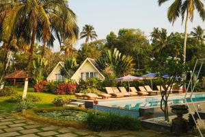ein Resort mit Swimmingpool, Stühlen und Palmen in der Unterkunft ETHER Marari Beachfront in Mararikulam