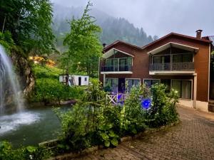 a house in the mountains with a waterfall at Uzungol Ada Bungalow in Uzungöl