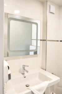 a white bathroom with a sink and a mirror at Family Hotel Albizia Beach in Varna City +31 photos