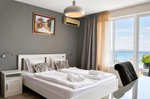 a white bed in a room with a window at Family Hotel Albizia Beach in Varna City