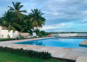 a swimming pool in a yard with palm trees at Quartos da Mell in Beberibe