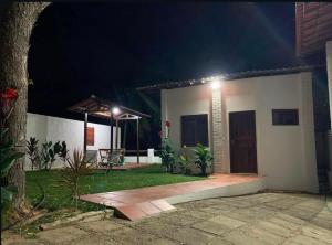 a house with a porch at night with a patio at Quartos da Mell in Beberibe