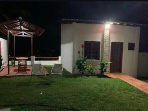 a house with a patio at night with chairs and a table at Quartos da Mell in Beberibe