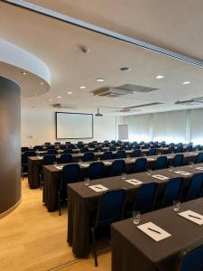 a conference room with tables and chairs and a screen at Gosset Hotel in Groot-Bijgaarden