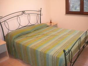 a bedroom with a bed with a striped blanket on it at Le case in collina - San Teodoro in Lu Lioni