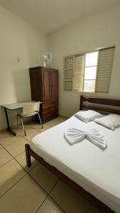 a bedroom with a bed with a dresser and a desk at Hotel Olympia in Cláudio