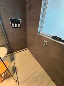 a bathroom with a shower with a table and a window at Penguin Beach House in Penguin +27 photos